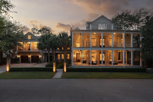 view of front of home featuring a garage, a balcony, ceiling fan, and a lawn