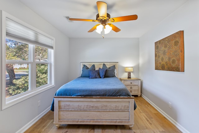 bedroom with ceiling fan, light wood-style flooring, and baseboards