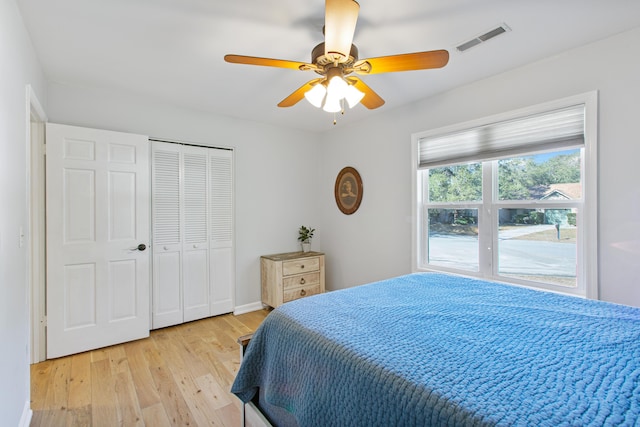 bedroom with a closet, visible vents, ceiling fan, and light wood finished floors