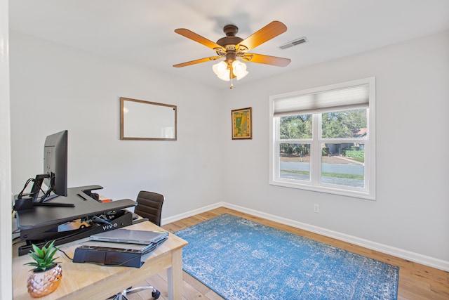 office featuring light wood finished floors, baseboards, visible vents, and a ceiling fan