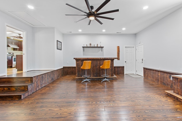 bar with a dry bar, a wainscoted wall, wood finished floors, stainless steel range with electric cooktop, and under cabinet range hood