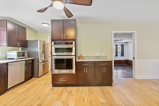 kitchen featuring light wood-type flooring, dark brown cabinetry, appliances with stainless steel finishes, and wainscoting