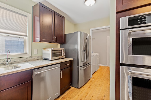 kitchen with dark brown cabinetry, a toaster, a sink, appliances with stainless steel finishes, and light wood-type flooring