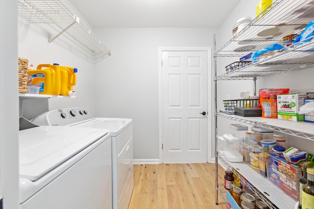 laundry area featuring washer and dryer, laundry area, light wood-style flooring, and baseboards