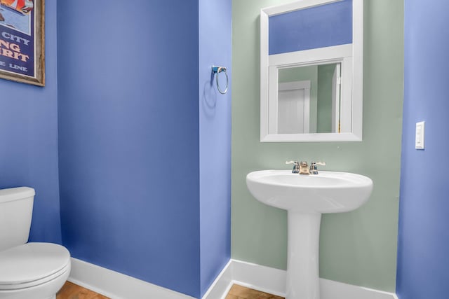 bathroom featuring toilet, baseboards, and a sink