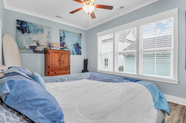 bedroom with wood finished floors, crown molding, baseboards, and a ceiling fan