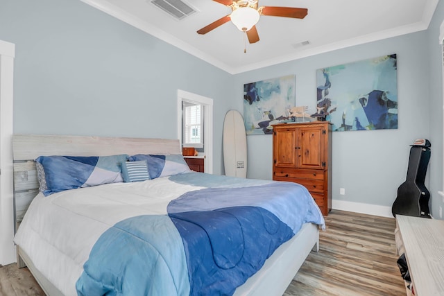 bedroom featuring crown molding, light wood-style flooring, baseboards, and ceiling fan