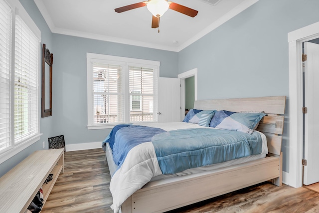 bedroom featuring multiple windows, wood finished floors, crown molding, a ceiling fan, and baseboards