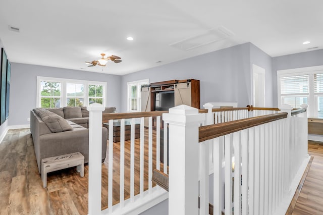 corridor with healthy amount of natural light, light wood-style floors, an upstairs landing, and recessed lighting