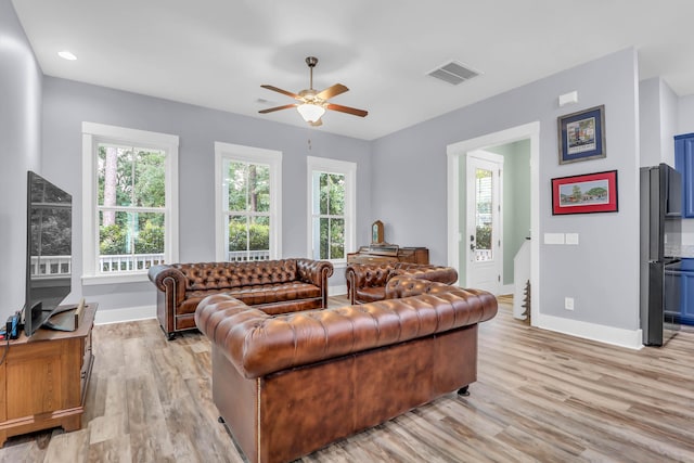 living area featuring baseboards, healthy amount of natural light, light wood-style floors, and ceiling fan