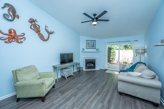 living area with vaulted ceiling, ceiling fan, wood finished floors, a fireplace, and baseboards