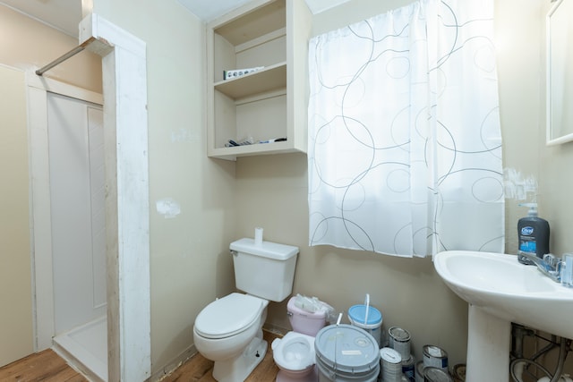 bathroom with hardwood / wood-style flooring, sink, a shower, and toilet