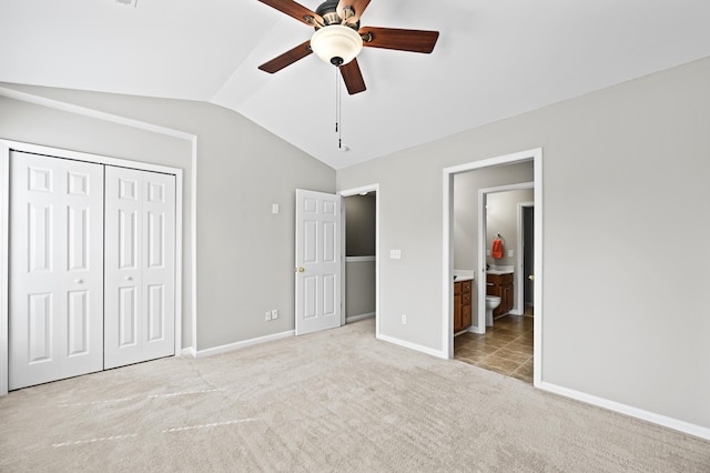 unfurnished bedroom featuring light carpet, vaulted ceiling, a closet, and ceiling fan