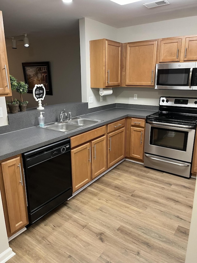 kitchen with sink, stainless steel appliances, and light hardwood / wood-style floors