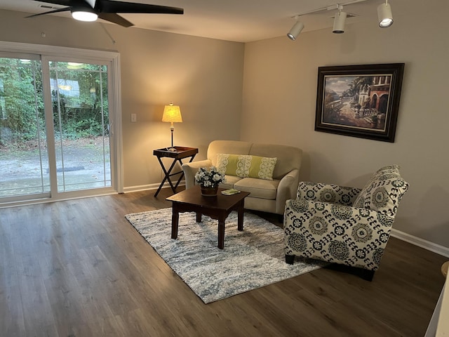 living room featuring dark wood-type flooring, rail lighting, and ceiling fan