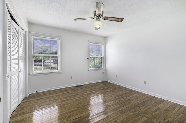 unfurnished bedroom with ceiling fan, dark hardwood / wood-style floors, a textured ceiling, and a closet