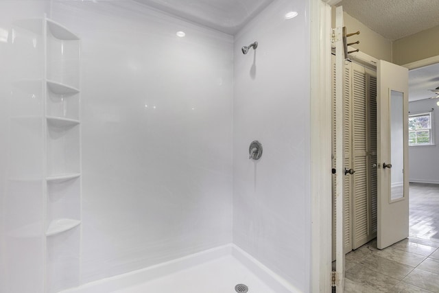 bathroom with tile patterned flooring, a textured ceiling, and walk in shower