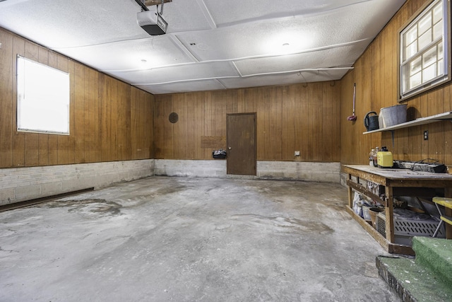 garage featuring a workshop area, a garage door opener, and wood walls