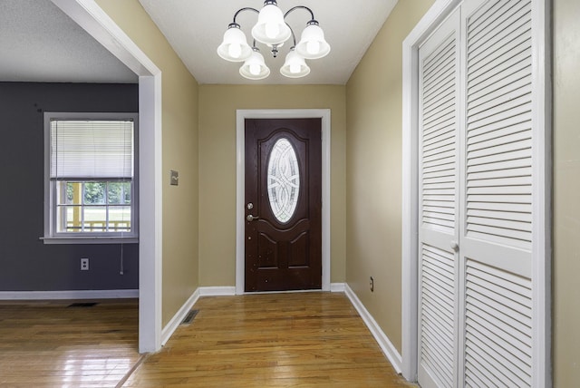 foyer entrance featuring hardwood / wood-style flooring, a textured ceiling, and a chandelier