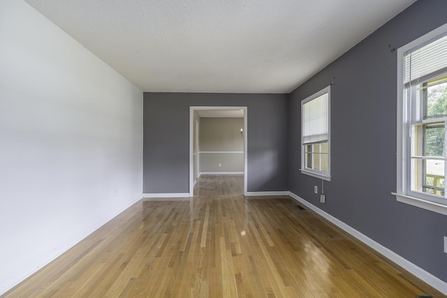 unfurnished room with light hardwood / wood-style floors and a textured ceiling