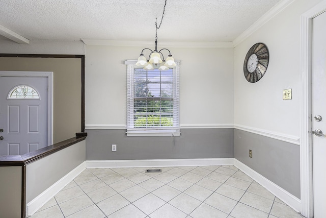 unfurnished dining area with a chandelier, light tile patterned floors, a textured ceiling, and ornamental molding