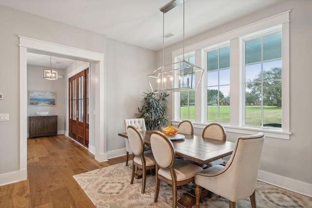 dining space featuring wood finished floors, visible vents, baseboards, and an inviting chandelier