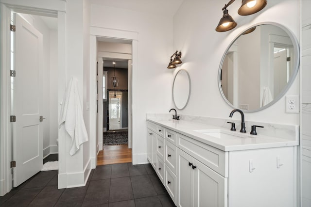 bathroom featuring tile patterned flooring, a sink, baseboards, and double vanity