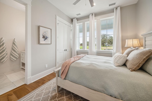 bedroom with a ceiling fan, baseboards, visible vents, and wood finished floors