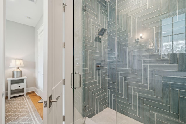 bathroom with a shower stall and baseboards