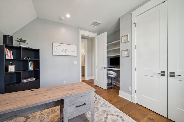 office space with lofted ceiling, visible vents, and wood finished floors