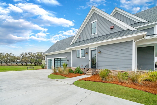 view of front facade with entry steps, an attached garage, driveway, roof with shingles, and a front yard