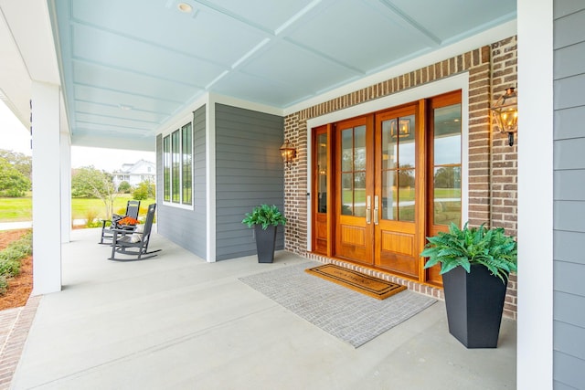 doorway to property with a porch and brick siding