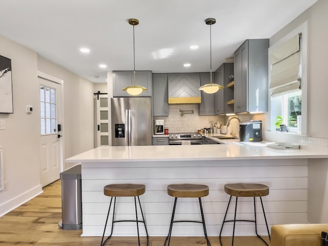 kitchen with stainless steel appliances, a kitchen breakfast bar, sink, and gray cabinetry