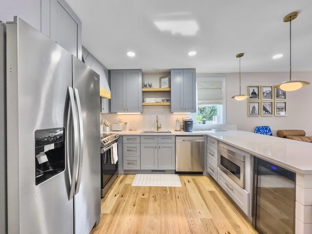 kitchen with appliances with stainless steel finishes, pendant lighting, tasteful backsplash, sink, and wine cooler