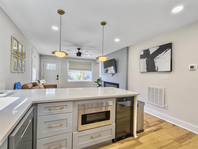 kitchen featuring wine cooler, light hardwood / wood-style flooring, stainless steel dishwasher, gray cabinets, and pendant lighting