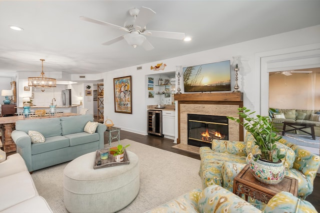 living room featuring hardwood / wood-style flooring, a stone fireplace, beverage cooler, and ceiling fan