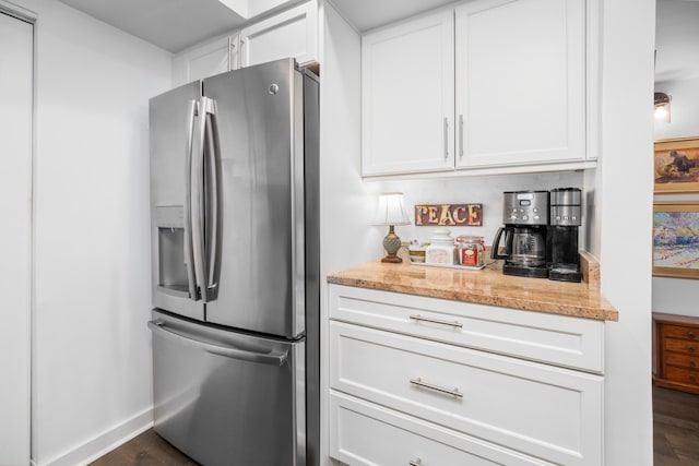 kitchen with dark wood-type flooring, light stone countertops, white cabinets, and stainless steel refrigerator with ice dispenser