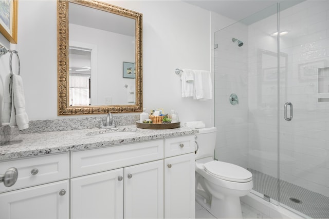 bathroom with a shower with door, vanity, and toilet