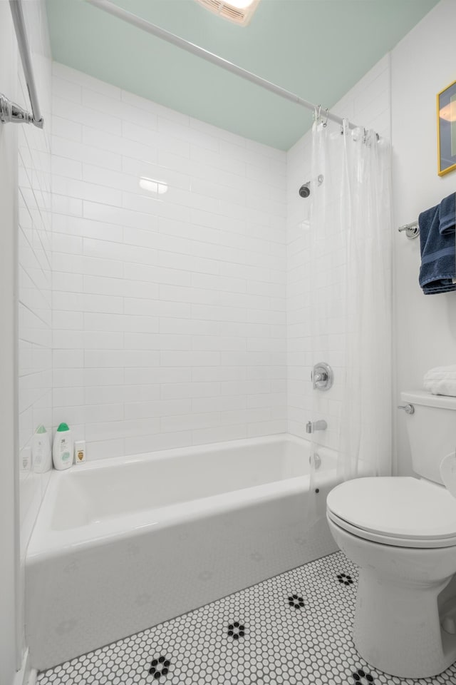 bathroom featuring tile patterned flooring, shower / tub combo, and toilet