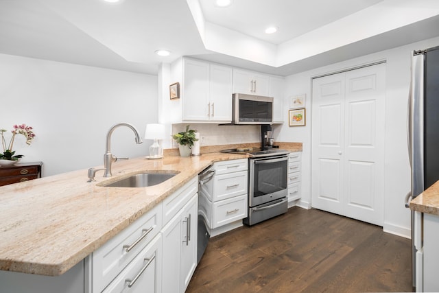 kitchen featuring sink, appliances with stainless steel finishes, light stone countertops, white cabinets, and kitchen peninsula