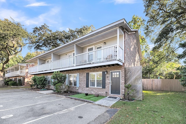 townhome / multi-family property with a balcony and a front lawn