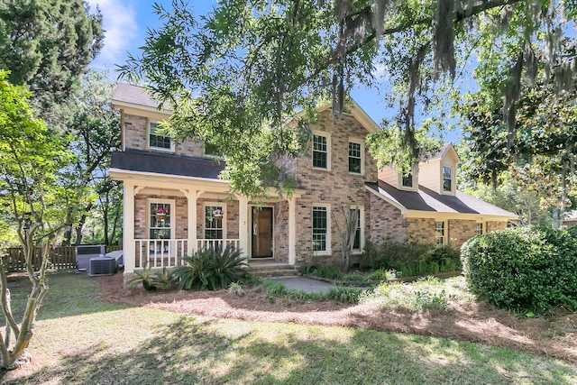 view of front of home with covered porch, brick siding, and central AC unit