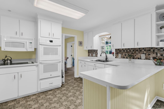 kitchen featuring white appliances, open shelves, a sink, a peninsula, and light countertops
