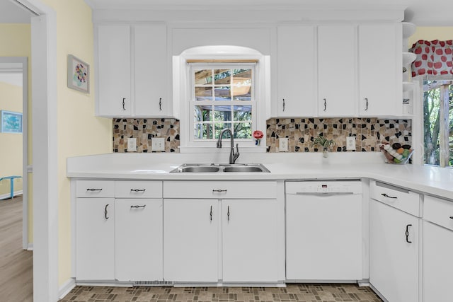 kitchen featuring white dishwasher, a sink, light countertops, backsplash, and white cabinets