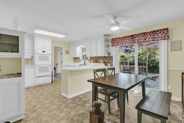 kitchen featuring a ceiling fan, a sink, double oven, a peninsula, and open shelves