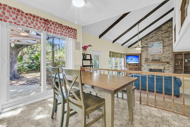 dining room with a ceiling fan, brick patterned floors, a fireplace, beamed ceiling, and high vaulted ceiling