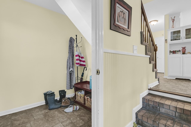stairway with stone finish floors and baseboards