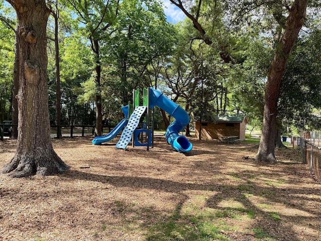 community playground with fence and view of wooded area