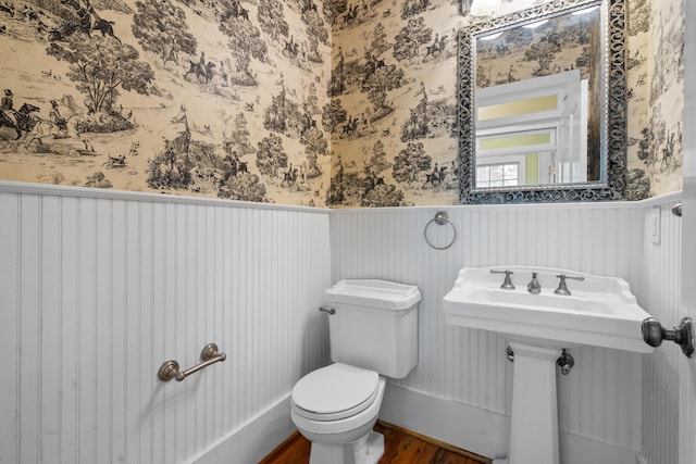 half bath with a wainscoted wall and wallpapered walls