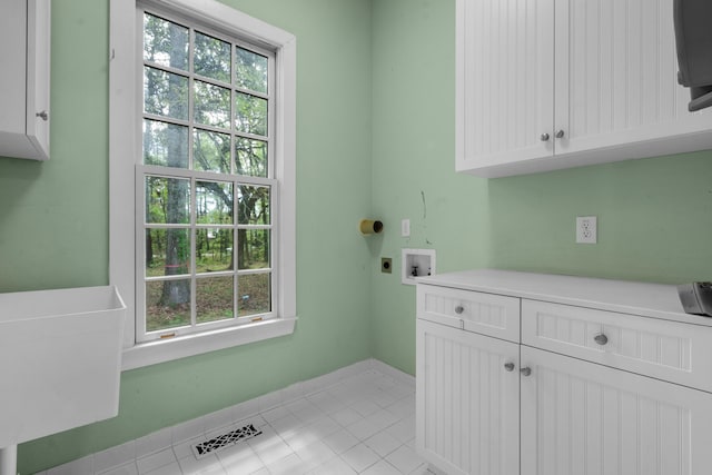 washroom featuring hookup for an electric dryer, baseboards, light tile patterned floors, washer hookup, and cabinet space